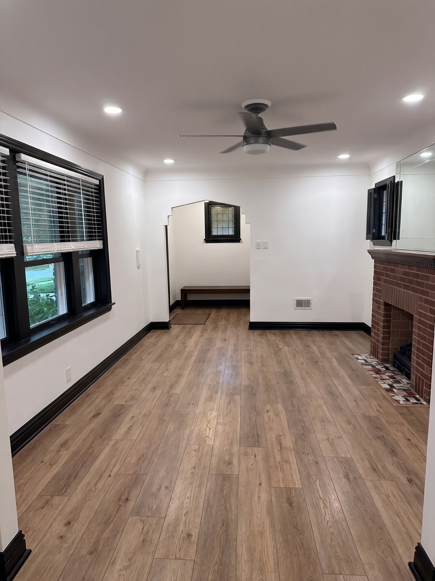Completed natural oak vinyl plank flooring in a bright living room with black trim