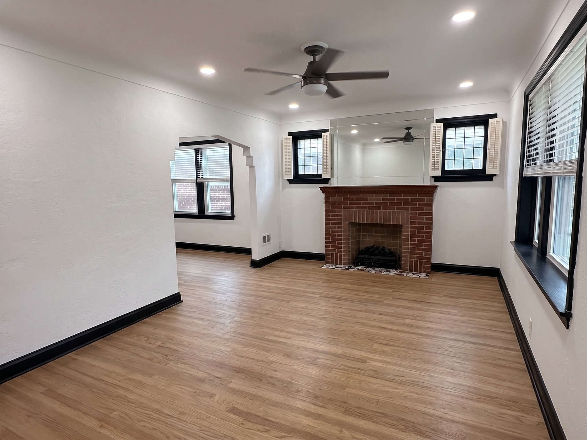 Completed oak vinyl plank flooring in a living room with a brick fireplace and black baseboards