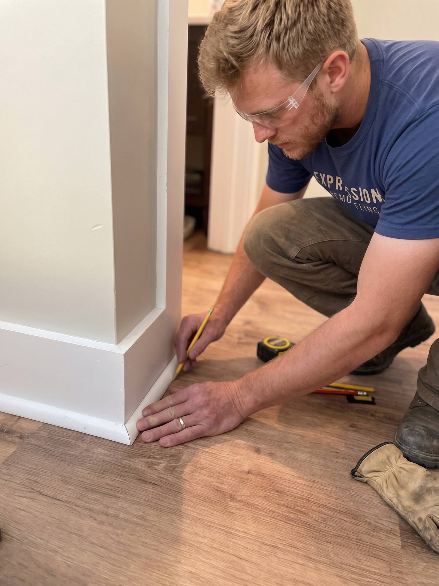 Expressions Remodeling installer fitting white quarter-round trim along a wall base